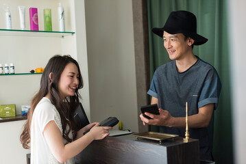 会計をする男性美容師と女性客
