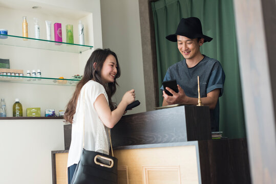 会計をする男性美容師と女性客