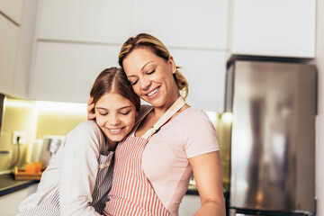 Smiling mother and daughter cooking together in the kitchen