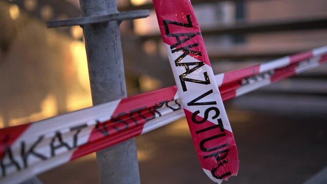 Red and white crossed ribbons with inscription Zakaz vstupu in Czech language on blurred background in city. Entry denied on signal ribbon closeup