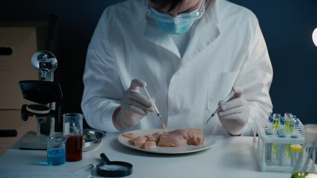 Male nutrition expert testing food products in laboratory. Lab assistant testing GMO chicken. Putting sample of chemical with injection in to test chicken meat. Genetically modified food, syringe.