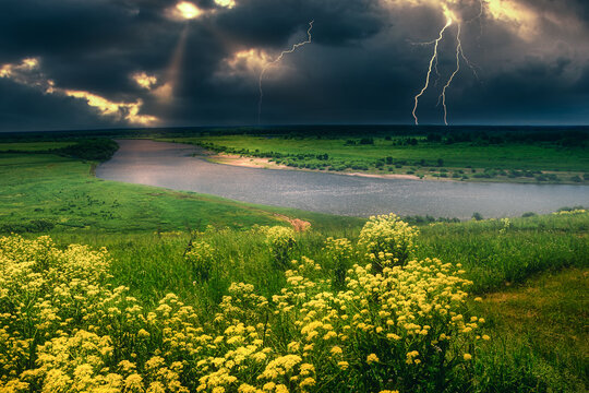 summer thunderstorm over the lightning river top view yellow meadow of flowers on the hill
