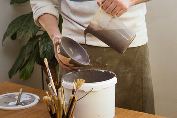 Potter Glazes Bowls in Workshop. Ceramic Artist Man glazing on master class. Pottery Making process, ceramic production