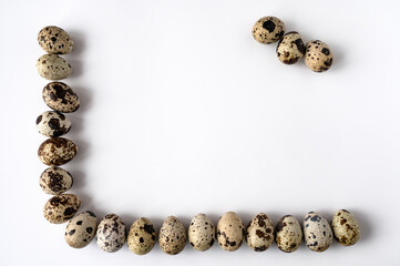 frame of quail eggs on perimeter of two sides on white background. Three eggs in the corner. Copy space