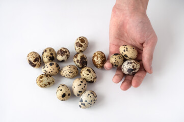 man's hand and fresh quail eggs on a white background. The concept of healthy eating and home cooking. Poultry farming, home farm