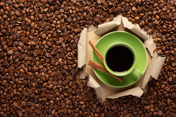 Cup of coffee and beans in torn paper. Coffee with espresso in cardboard background