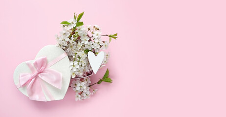 gift box with white heart and cherry flowers on abstract pink background. spring season, festive composition. romantic gift for women. top view. copy space