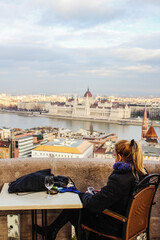 Fototapeta na wymiar Woman looking at her phone in Budapest overlooking the Parliament