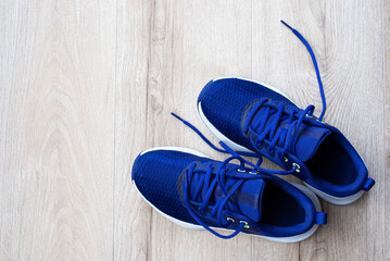 A pair of blue sneakers on a light wooden laminate. Sports theme without people.