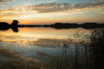 Obraz premium Reflection of clouds in the lake water after sunset, Stankow, Poland