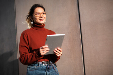 Pretty smiling asian woman holding digital tablet