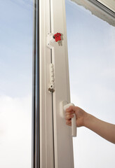 A small child is trying to open a window in an apartment. Lock to protect windows from children. The concept of protecting a child from falling out of windows