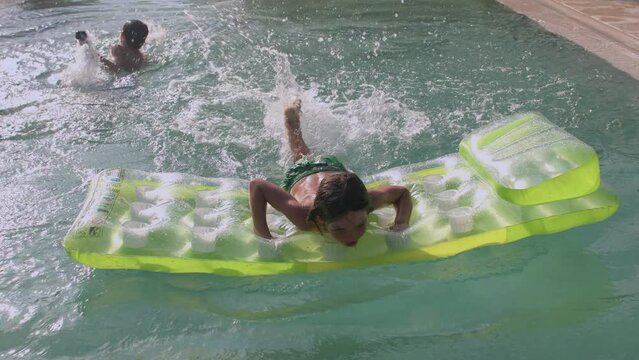 Child uses green inflatable mattress while swimming in a pool during summer vacations. The ability to swim and the scare of drowning, aquaphobia. Precautions on the water. IT, Borgagne, 6.10.2021 