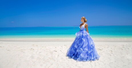 Fototapeta na wymiar Luxury fashion. Elegant fashion model. Stylish female model in elegant long gown dress on the Maldives beach. Elegance. Bride on Maldives. Bridal fashion. Classy woman in amazing blue dress. Couture.