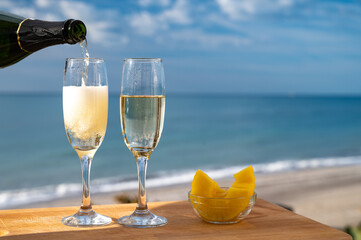 Outdoor breakfast with Spanish cava sparkling wine and pineapple with view on blue sea and sandy...