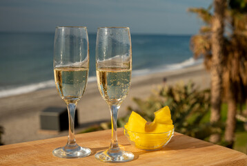 Outdoor breakfast with Spanish cava sparkling wine and pineapple with view on blue sea and sandy beach in Marbella, Costa del Sol vacation destination, Andalusia, Spain