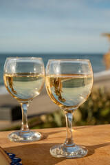 Glasses of Spanish dry white wine served on andalusian style board with blue ornament on beach terrace with view on Mediterranean sea