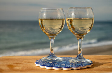 Glasses of Spanish dry white wine served on andalusian style board with blue ornament on beach...