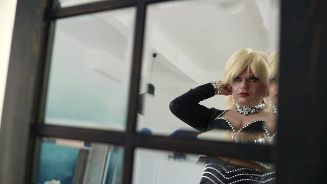 Man with make-up in the mirror, travesty diva. A drag queen poses in front of a mirror.