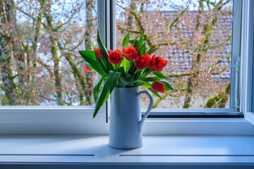 tulips in a vase in front of a window with a tree in the background 