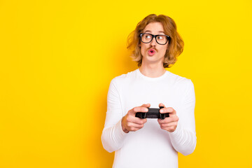 Photo of impressed funky guy wear white shirt spectacles holding playstation looking empty space isolated yellow color background