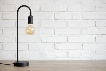 modern lamp on the table over white brick wall background with copy space