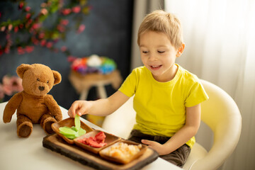 Cute little preschool child, boy, eating dried fruits at home, strawberries, melon, pineapple
