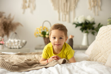Fototapeta premium Cute little preschool boy with his pet dog, playing together in bed