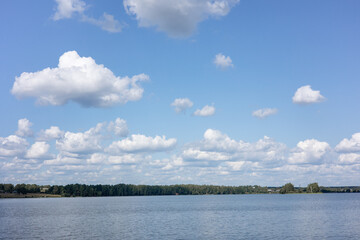 Summer countryside landscape with blue sky and calm water of river.
