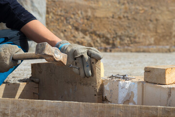 Hands of man working in construction site nailing in the wood with a hammer