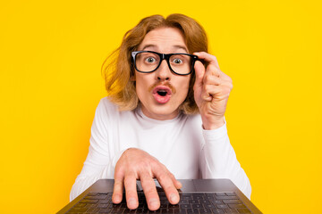 Photo of funny impressed guy dressed white shirt arm glasses writing modern device isolated yellow...