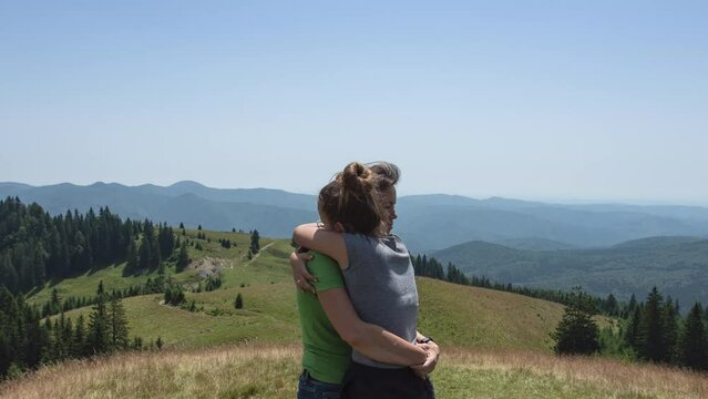 Mother with teenage daughter outdoors in the mountains hugging - camera revolves around, stop motion animation