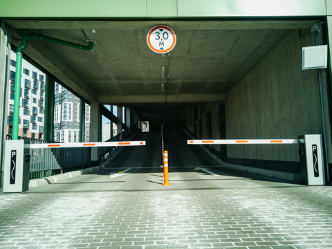 Entrance to the covered multi-level parking for cars with a barrier and video surveillance.