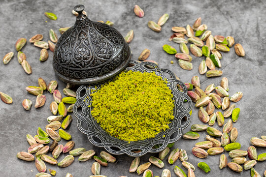 Pistachio powder on dark background. It's surrounded by pistachios. close-up. local name toz antep fistik