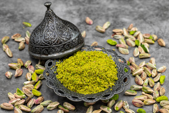 Pistachio powder on dark background. It's surrounded by pistachios. close-up. local name toz antep fistik