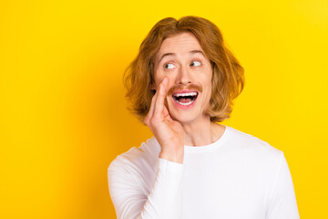 Photo of funny carefree man looking empty space talk about new advertisement promotion isolated on yellow color background