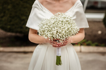 beautiful wedding bouquet of white flowers in the hands of the bride, gypsophila