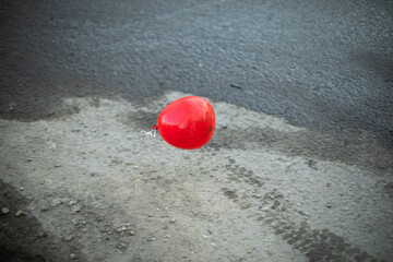 Red ball on background of asphalt. Abstract art. Sphere made of plastic.