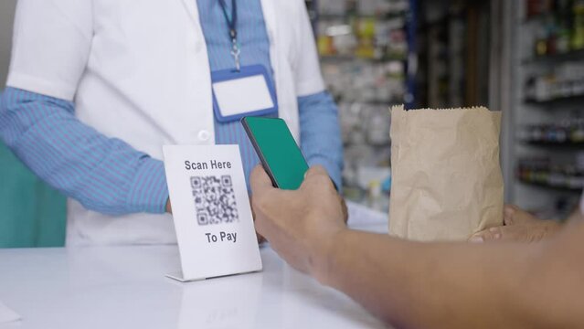 close up shot of Customer hands paying by scanning qr code at medical shop for medicine purchase - concept of cashless or contactless transaction, technology and secure payment system.