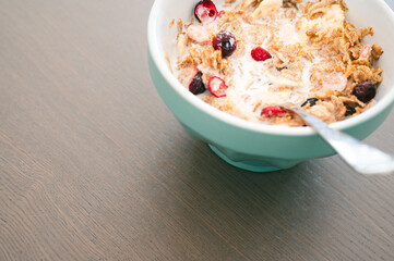 Bowl of muesli isolated on dark wooden background. Fresh oats with fruits and milk for healthy breakfast.