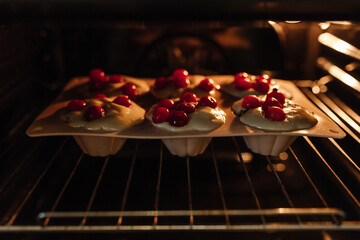 The process of baking cupcakes in the oven. Dough for baking cupcakes with cherries.