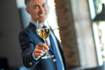 Smiling man with a glass of wine in hands