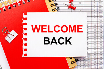 Against the background of the reports, there are red and brown notepads, a white paper clip, red buttons and a white sheet of paper with the text WELCOME BACK. Business concept