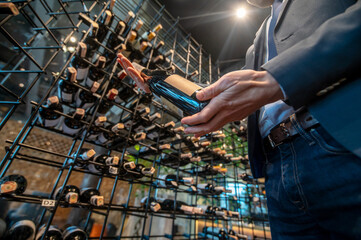 A man in a wine store with lots of bottles with wine