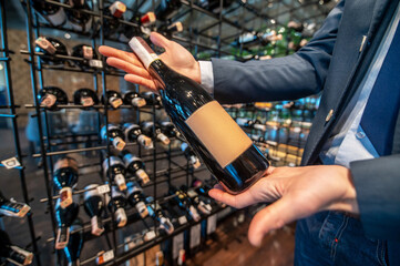 A man in a wine store with lots of bottles with wine