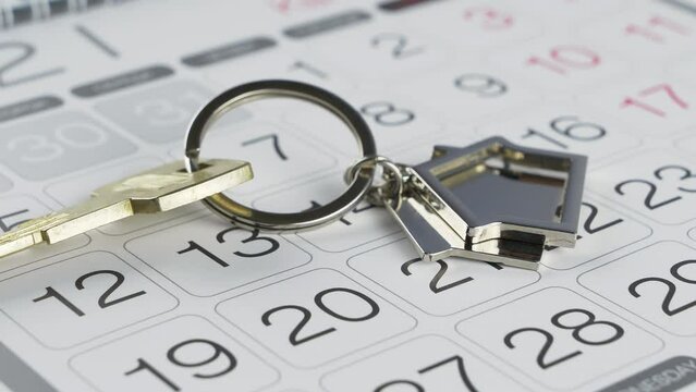 House keys on keychain on calendar. Buying or selling a house or real estate, rent payment time.