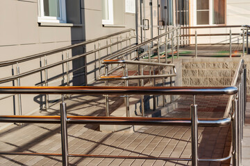 A ramp and metal railings at the entrance to the residential building for the convenience of people with disabilities and the elderly.