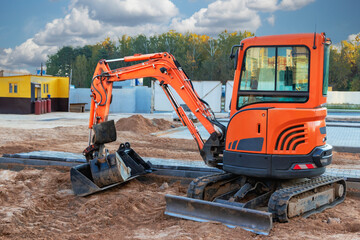 Mini excavator at the construction site. Compact construction equipment for earthworks. - obrazy, fototapety, plakaty