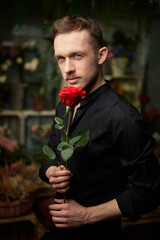 Serious elegant sexy macho man with mustache holding one red rose in hand, looking at camera...