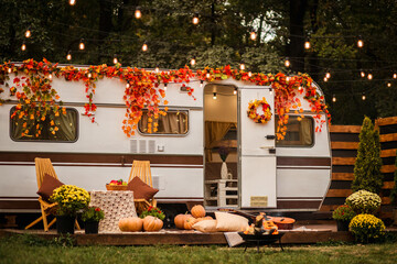 Wooden table and chairs near the trailer. camping autumn. photo studio. Trailer on the background of the forest.Flowers in pots